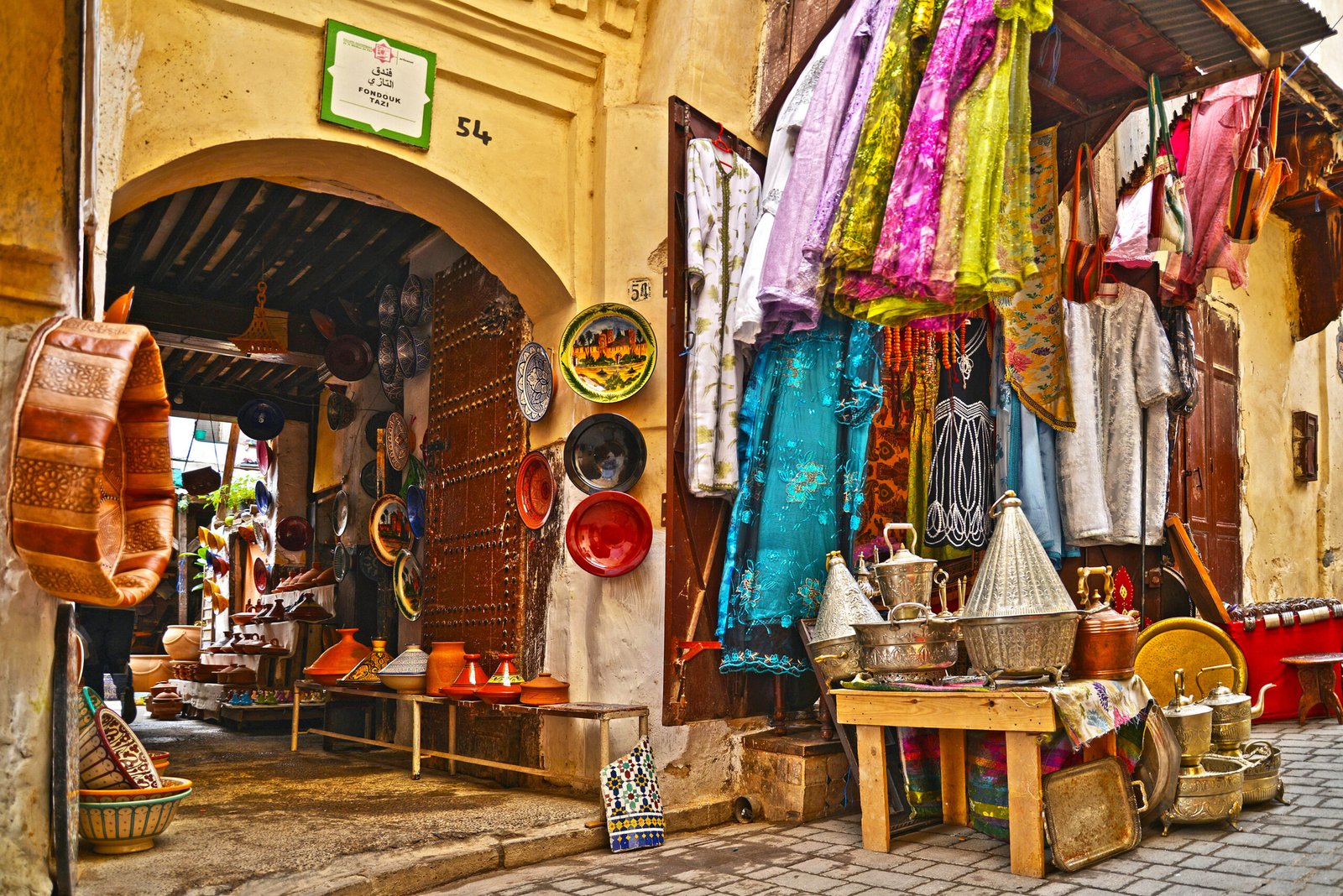 Tourists exploring narrow alleys of Marrakech medina with guide Traditional Moroccan tiles and fountain in a secret medina garden Local artisan crafting leather goods in a Marrakech souk moroccotravelbliss